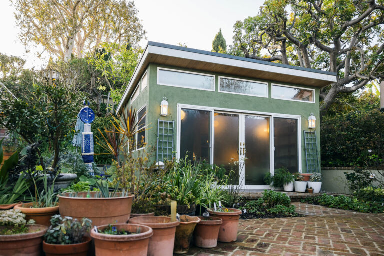 Green backyard studio shed with sliding glass doors
