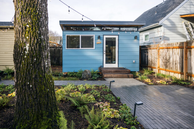 Blue backyard shed with pathway and string lights