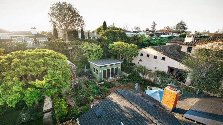 Aerial view of backyard shed surrounded by trees and homes