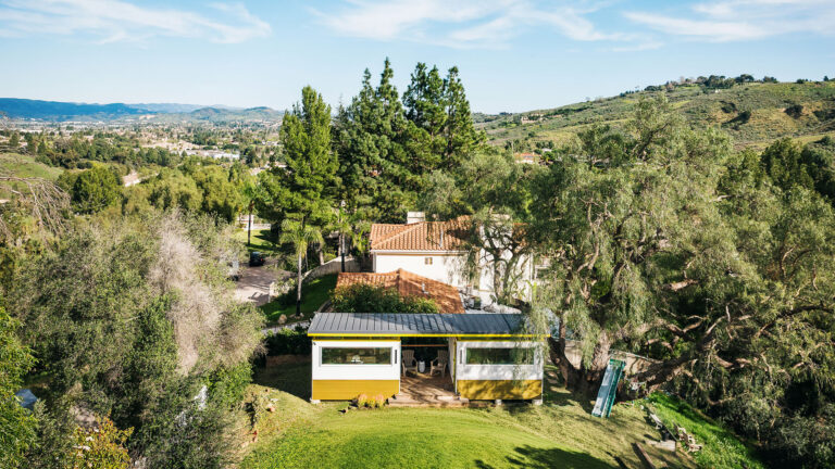 Modern prefab shed on hillside with deck and trees