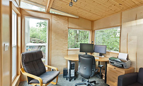Interior home office setup inside wood-paneled shed